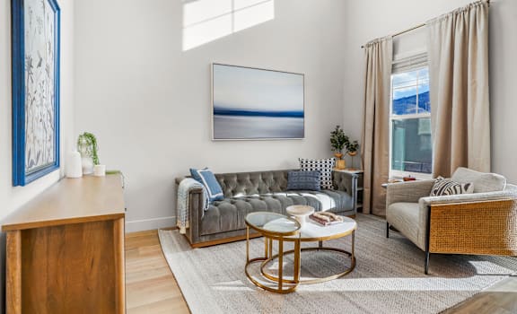A living room with a grey sofa, a wooden side table, and a large painting on the wall.