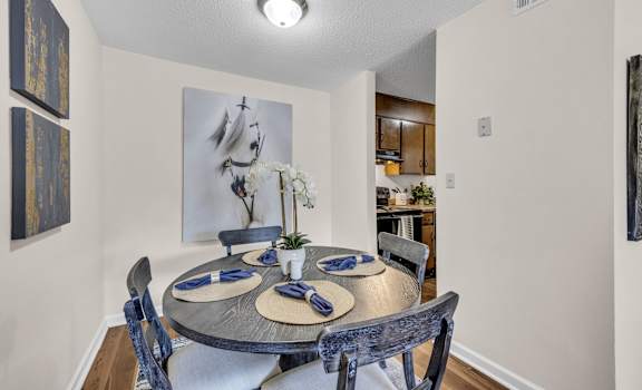 a dining room with a table and chairs   and a kitchen
