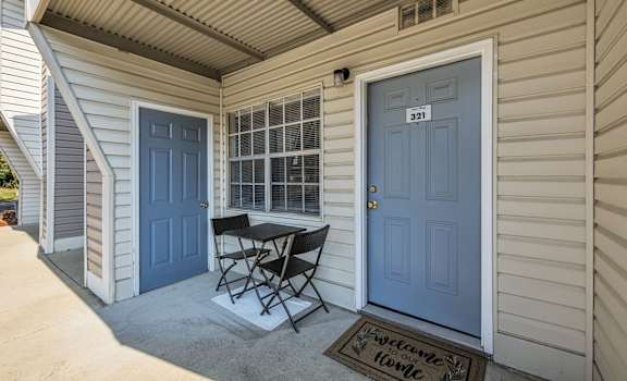 a patio with a table and chairs in front of a blue door