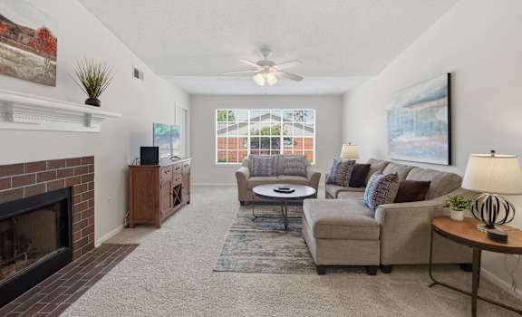 A living room with a fireplace and a ceiling fan.