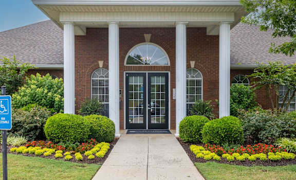 the front entrance of a brick building with columns and a porch