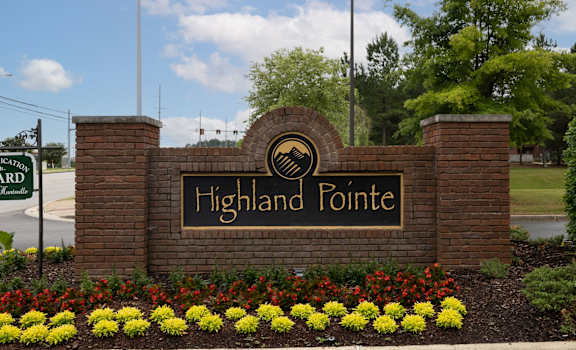 the sign for highland pointe in front of a brick wall with flowers