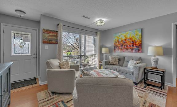 A living room with a grey couch and a painting on the wall.