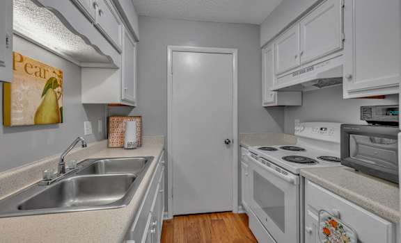 A kitchen with white cabinets and a white door.