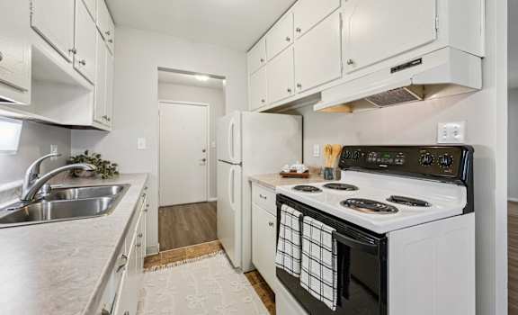 A white kitchen with a black stove top oven.