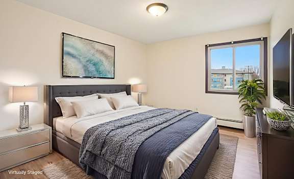 A bedroom with a bed, nightstand, and a painting on the wall.