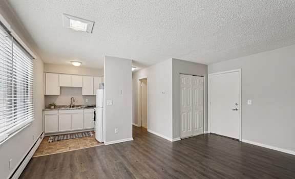 A kitchen with white cabinets and a window with blinds.