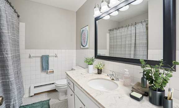A bathroom with a white sink, toilet, and a mirror above the sink.