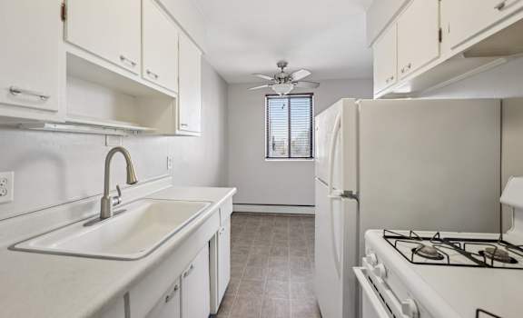 A kitchen with a white stove, sink, and cabinets.