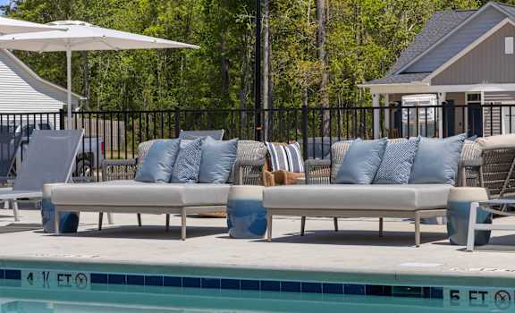 a poolside seating area with couches and chairs next to a swimming pool