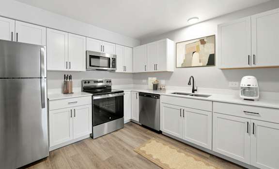 A modern kitchen with white cabinets and stainless steel appliances.