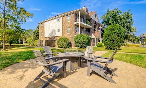 A patio with a table and chairs is in front of a brick apartment building.