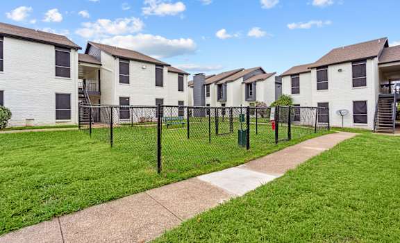 A row of white houses with green lawns and a clear blue sky.