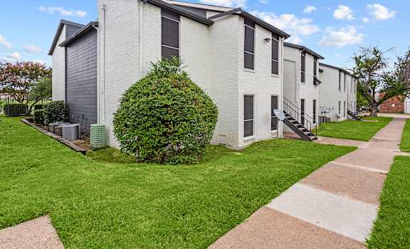 A white building with a green bush in front of it.