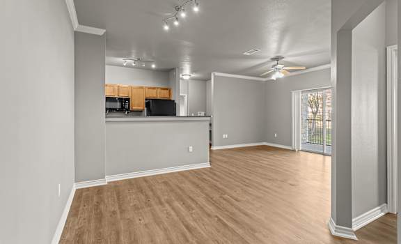 A spacious room with wooden flooring and a ceiling fan.