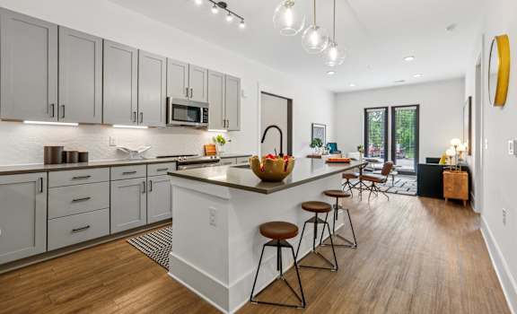 A modern kitchen with a white island and wooden floors.