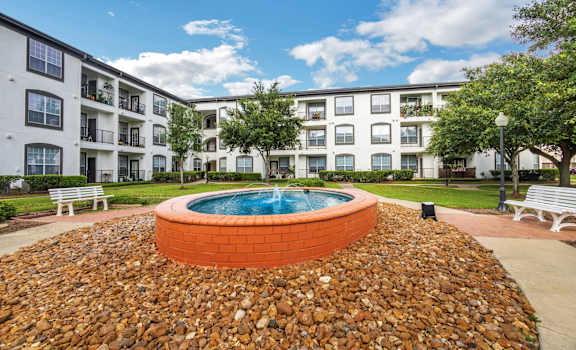 an exterior view of an apartment building with a pool and rocks