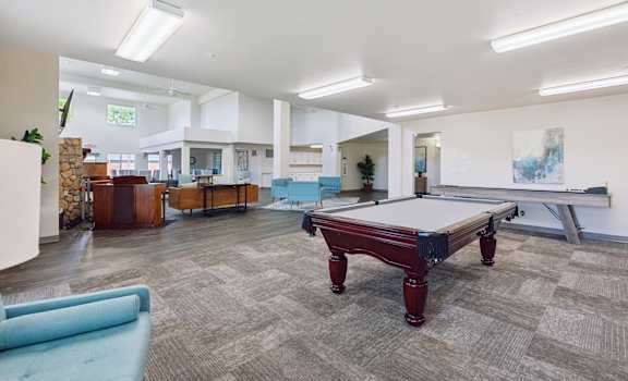 a games room with a pool table in the middle