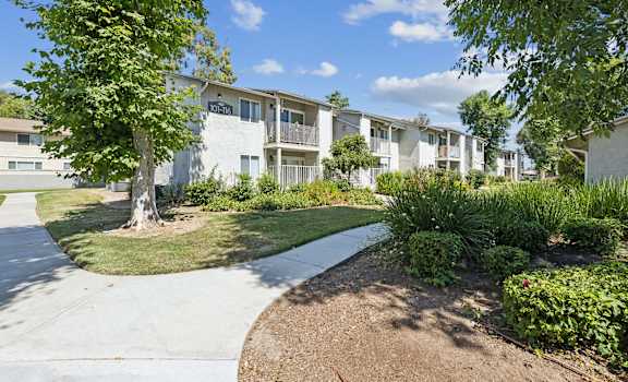 an apartment building with a sidewalk and grass and trees