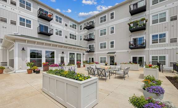 a courtyard with tables and chairs in front of an apartment building