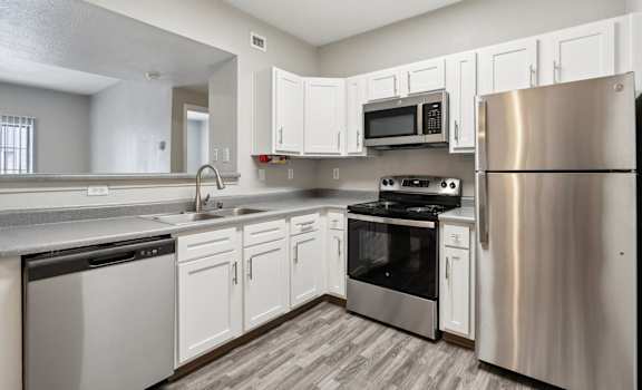 an empty kitchen with stainless steel appliances and white cabinets