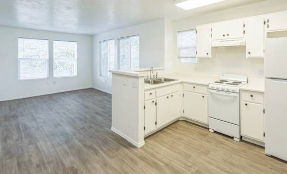 an empty kitchen with white appliances and white cabinets