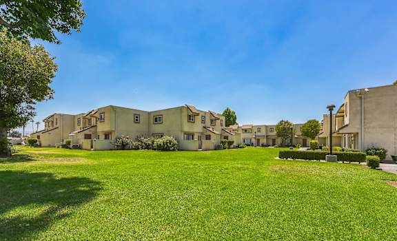 a row of apartments with a green lawn and blue sky