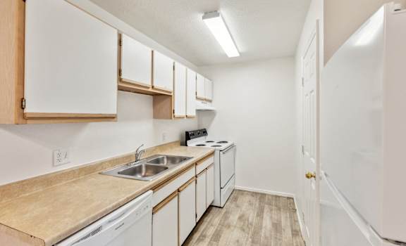 a kitchen with white appliances and white cabinets and wood flooring