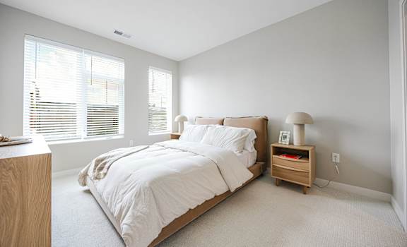 A bedroom with a large bed and a nightstand with a lamp.
