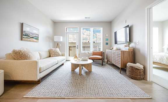 A living room with a white couch, a coffee table, and a painting on the wall.