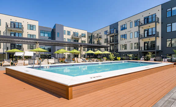 A pool surrounded by wooden deck and buildings.