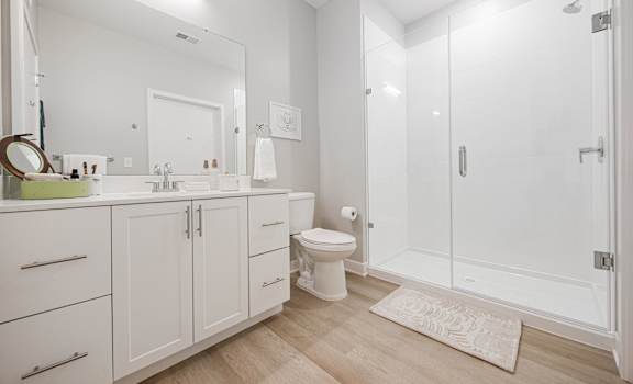 A white bathroom with a toilet, sink, and shower.