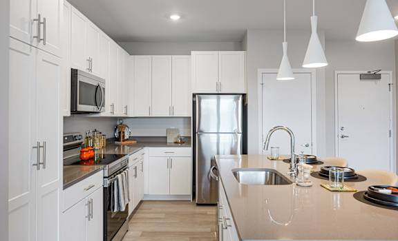 A modern kitchen with white cabinets and a stainless steel refrigerator.