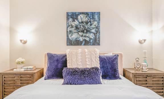 A bed with a white comforter and a blue floral print above it.
