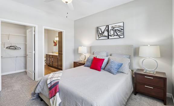 A bedroom with a bed, two lamps, and a ceiling fan.