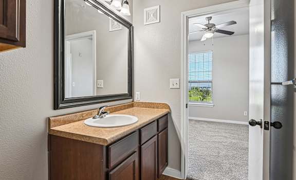 A bathroom with a sink, mirror, and a door leading to a hallway.