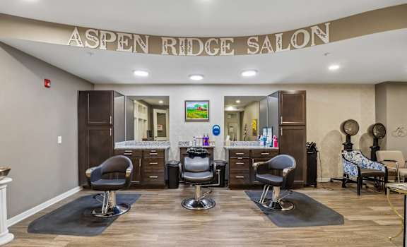 A salon with chairs and a counter with a sign that says "Aspen Ridge Salon".