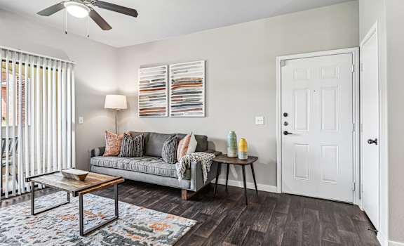 A living room with a grey couch, a coffee table, and a ceiling fan.