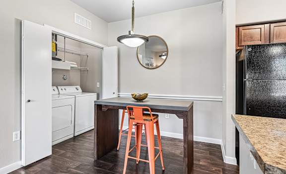 A kitchen with a black fridge, white oven, and a wooden table with a bowl on it.