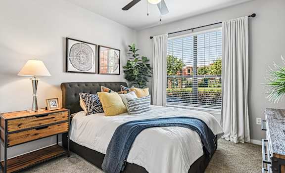 A bedroom with a bed, nightstand, and a ceiling fan.