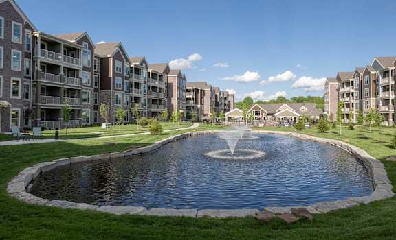a large pond with a fountain in front of an apartment building at The Clearing at ONE28, Olathe, 66062