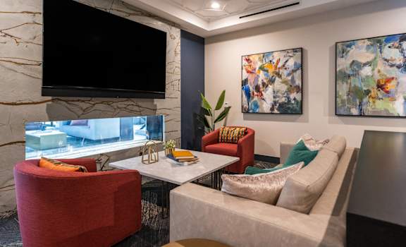a living room with couches and chairs and a television at The Clearing at ONE28, Olathe, 66062