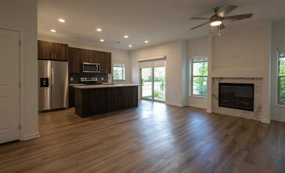 an empty living room with a fireplace and a kitchen at The Clearing at ONE28, Olathe, 66062