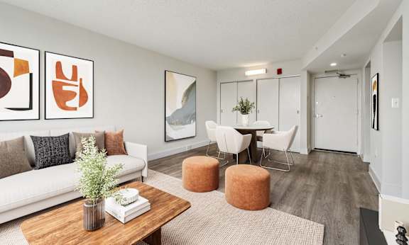 A living room with a white couch, a wooden coffee table, and a dining table with chairs.