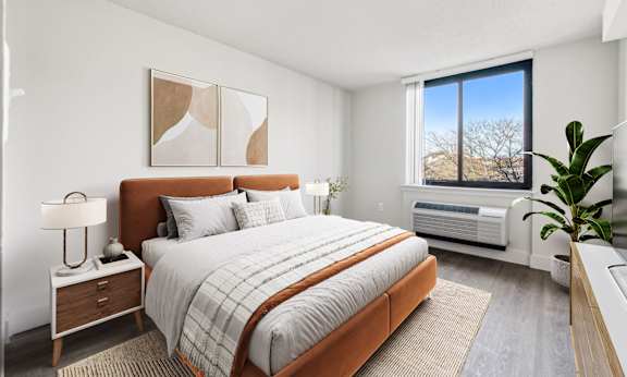 A bedroom with a large bed and a window overlooking a snowy landscape.