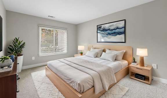 A bedroom with a large bed and a painting on the wall.
