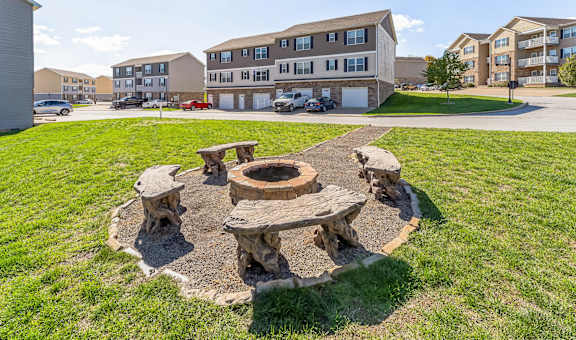 a fire pit with wooden benches in front of an apartment building