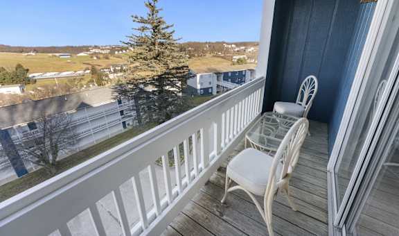 a balcony with two chairs and a glass table on it