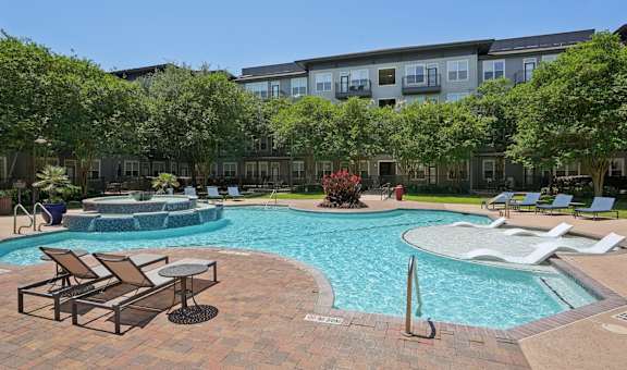 A large outdoor swimming pool surrounded by lounge chairs and umbrellas.