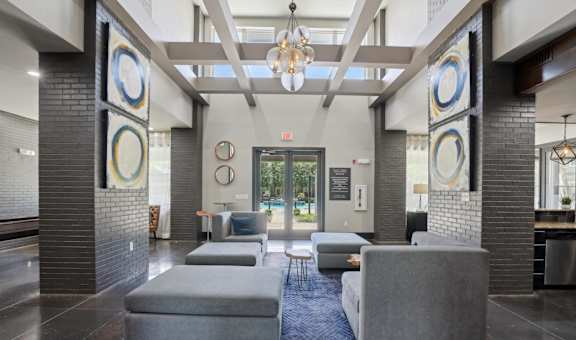 A modern lobby with grey couches and a blue rug.